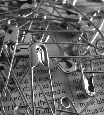 Photograph of safety pins on a printed page